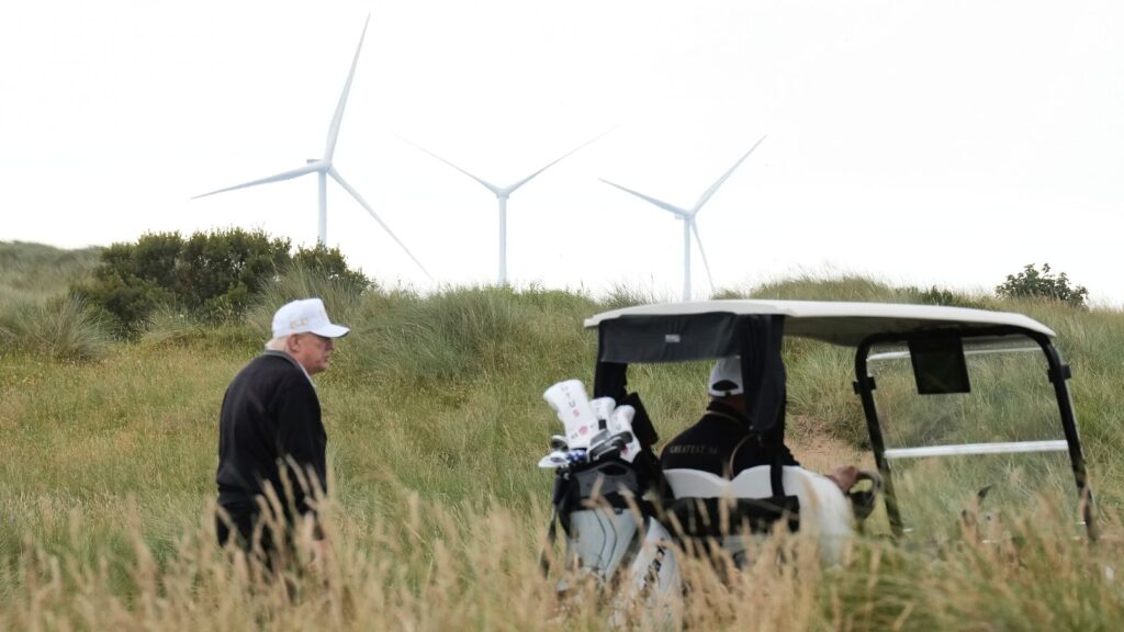 Donald Trump walks backdropped by wind turbines during an opening ceremony for the Trump International Golf Links golf course. Pic: AP