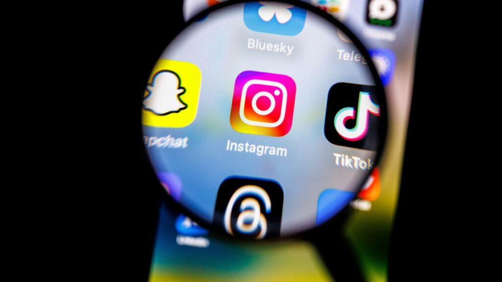 The logo of the Instagram app can be seen through a magnifying glass on the display of a smartphone on February 19, 2025. FIle pic: AP
